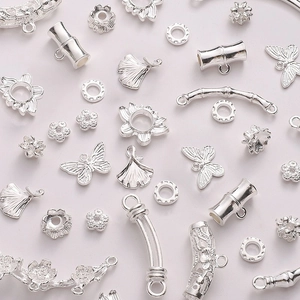 Macro shot of silver alloy carved beads and butterfly charms for DIY jewelry making
