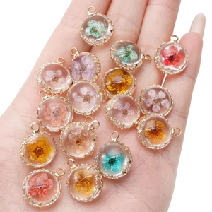 Detailed palm view of 18K gold-plated DIY pendants with colorful dried flowers in resin