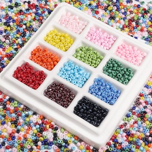 Vue macro de perles de rocaille en verre 3mm en 12 couleurs dans un plateau de tri blanc
