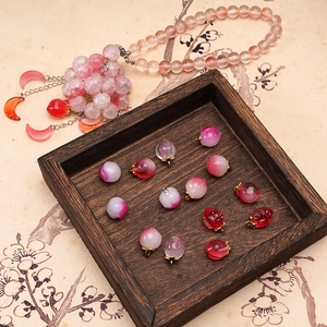 Detail showing various pink peach glass pendants on a traditional Chinese style background