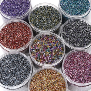 Top view of nine colorful glass bugle beads in transparent jars for DIY jewelry making