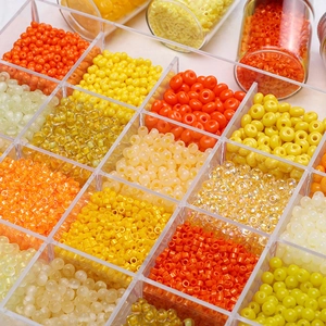 Vue détaillée de perles de rocaille orange dans une boîte de rangement transparente