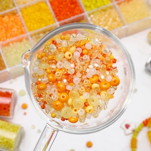 Mélange de perles en verre orange et crème 2-4mm dans un plateau pour bijoux DIY créatifs