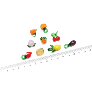 Vista macro de cuentas de vidrio artesanales con forma de frutas y verduras para joyas DIY