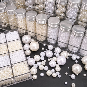 Detailed view of mixed size white and cream ABS pearls in storage bottles and glass jars