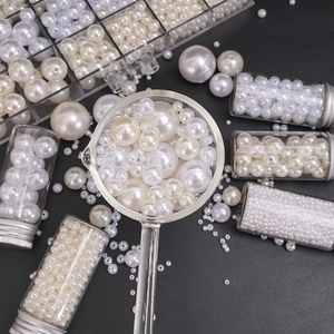 Macro shot of assorted white and beige ABS craft pearls in a grid organizer box