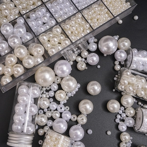 Detailed view of assorted white and ivory ABS imitation pearls with storage containers