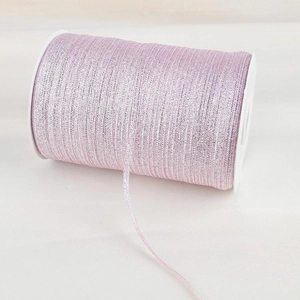 Detailed macro view of light pink metallic glitter ribbon on white plastic spool roll