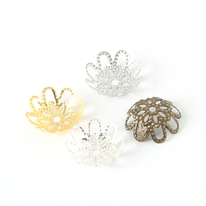 Detailed macro of hollow flower bead caps in gold, silver, and bronze for DIY jewelry