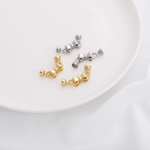 Dettaglio di chiusure per gioielli a forma di fiocco oro e argento su vassoio in ceramica