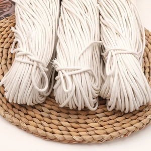 Trois rouleaux de corde en coton beige pour DIY sur un support en paille tressée naturel