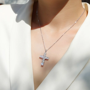 Macro view of S925 sterling silver cross pendant with shimmering moissanite on model