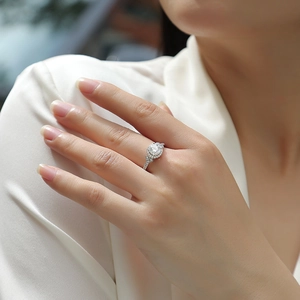 Primer plano de un anillo halo de moissanita color D llevado en la mano con diamantes