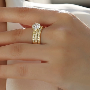 Macro shot of three-piece stackable gold rings featuring round moissanite on finger