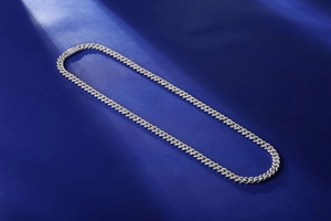Detailed close-up of a silver Cuban link chain with pavé-set moissanite on silk background