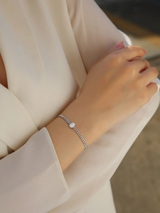 Macro shot of silver curb chain bracelet with oval moissanite on a model's wrist