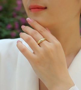 Close-up of a gold star engraved ring with white zircons worn on a finger