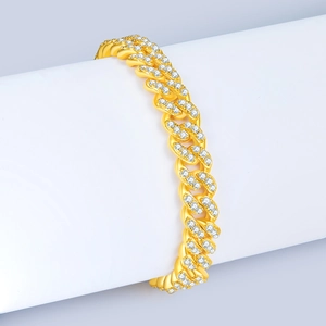 Détail d'un bracelet gourmette doré serti de zircons sur un présentoir de bijoux blanc