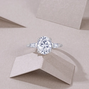 Dettaglio macro dell'anello in moissanite taglio ovale con pietre trapezoidali su champagne