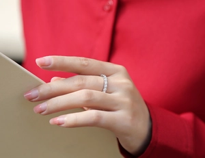 Eternity ring with round moissanite stones in S925 silver worn on hand over red fabric