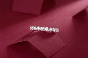 Artistic display of silver moissanite band ring on elegant red geometric background