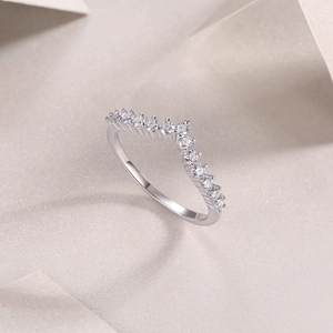 Détail macro d'une bague en V argentée sertie de pierres blanches sur un fond beige doux