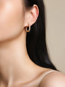 Gros plan de créoles plaquées or 18 carats serties de moissanite sur l'oreille