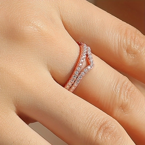 Macro shot of V-shaped rose gold wishbone ring with pave-set moissanite on a finger