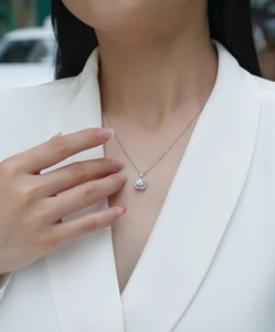 Close-up of a square lab-grown diamond pendant necklace on a woman in a white suit