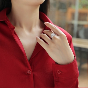 Detailed close-up of a silver Moissanite halo ring with side diamonds on a model