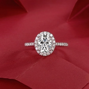 Macro shot of oval cut moissanite ring with halo setting on red textured background