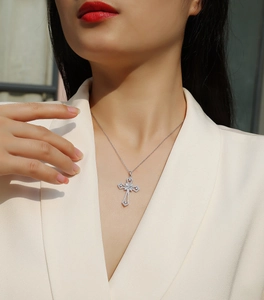 Gros plan d'un collier pendentif croix en argent S925 avec moissanite porté par un mannequin