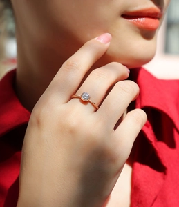 Primo piano di un anello minimalista in oro rosa con moissanite rotonda sul dito