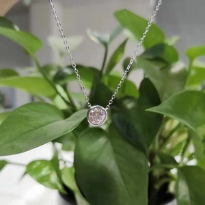 Vista ravvicinata di un ciondolo solitario tondo in moissanite con incastonatura a castone
