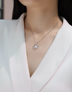 Detail of a 925 silver double heart pendant with round diamond center on a female model