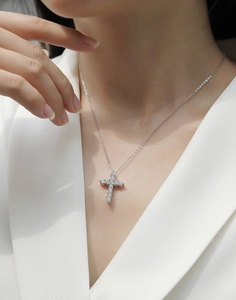 Close-up of sparkling diamond cross pendant on S925 silver chain with white blazer