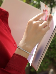 Close-up of minimalist S925 sterling silver bangle with pavé moissanite on model wrist