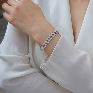Makroaufnahme eines funkelnden silbernen Panzerarmbands mit Moissanit-Besatz am Handgelenk
