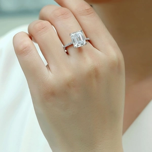 Anello con moissanite taglio smeraldo e pavé di diamanti indossato su un dito