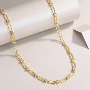 Gros plan d'un collier chaîne trombone doré avec des accents étincelants en zircon blanc