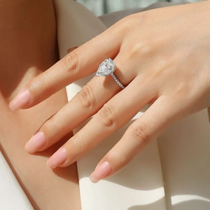 Gros plan d'une bague en moissanite taille poire avec anneau pavé sur le doigt du modèle