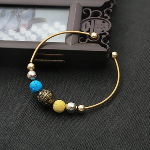 Adjustable golden open bangle with blue and yellow lava beads and vintage engraved charms