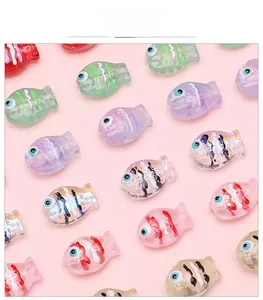Flat lay macro of fish-shaped glass beads in various colors for DIY jewelry making