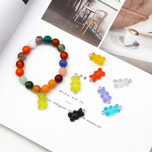 Gros plan de breloques oursons en résine colorée et bracelet perlé sur fond artistique