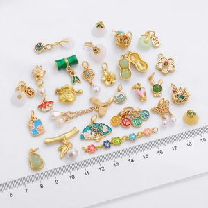 Detailed view of Chinese style gold plated charms with size ruler for scale