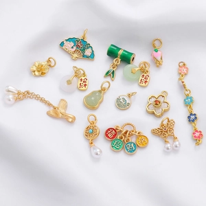 Detailed close-up of gold-plated Chinese fan and peanut charms with enamel and pearls