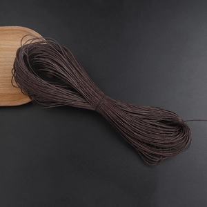 Close-up of 1mm dark brown waxed cotton cord for jewelry making on black background