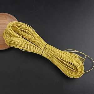 Close-up of 1mm bright yellow waxed cotton cord roll for DIY jewelry making on black background