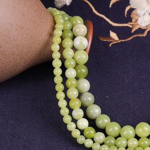 Close-up of semi-translucent green jade round beads in 4mm, 6mm and 10mm sizes for DIY
