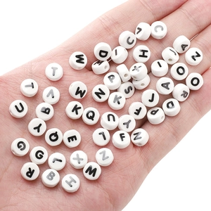 Macro shot of 8x4mm white ceramic alphabet beads with black letters for DIY jewelry